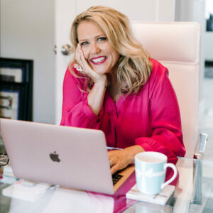 Neen sitting at her desk with her laptop and coffee